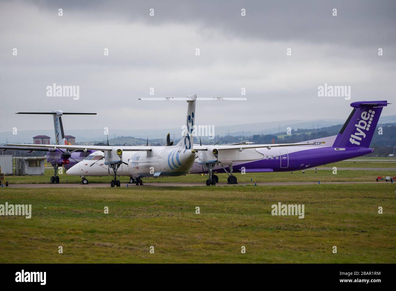 Glasgow, UK. 27 March 2020. Pictured: Grounded Flybe De Havilland Canada Dash 8 Q400 Aircraft seen parked up on the tarmac by the Emergency Rendezvous point at Glasgow Airport.  The Coronavirus Pandemic has been responsible for the UK shutdown aviation bringing Glasgow Airport to look more like a ghost town. Credit: Colin Fisher/Alamy Live News. Stock Photo