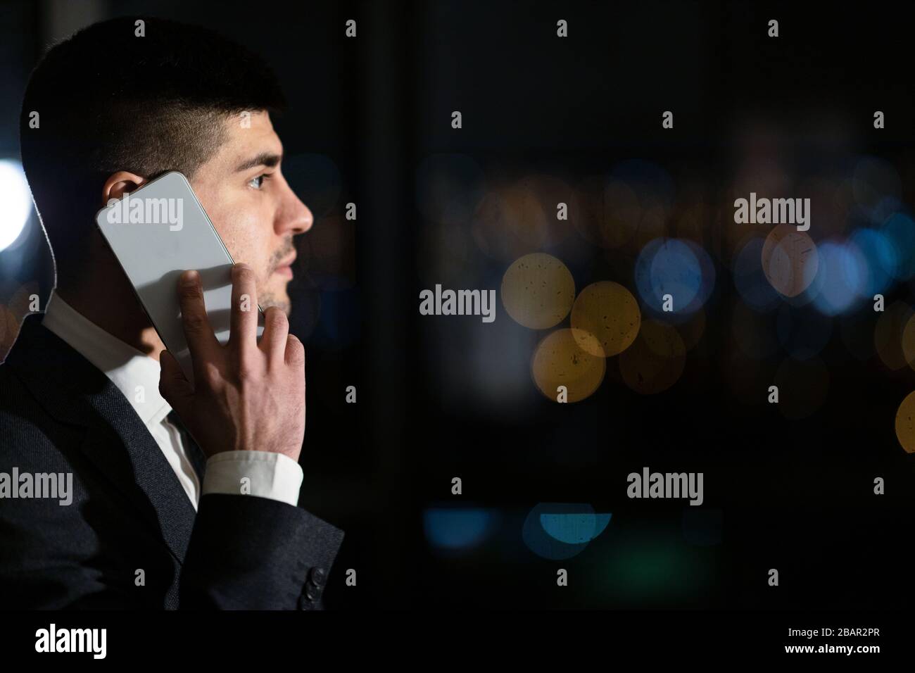 Serious Businessman Talking On Mobile Phone Standing In Office, Side-View Stock Photo