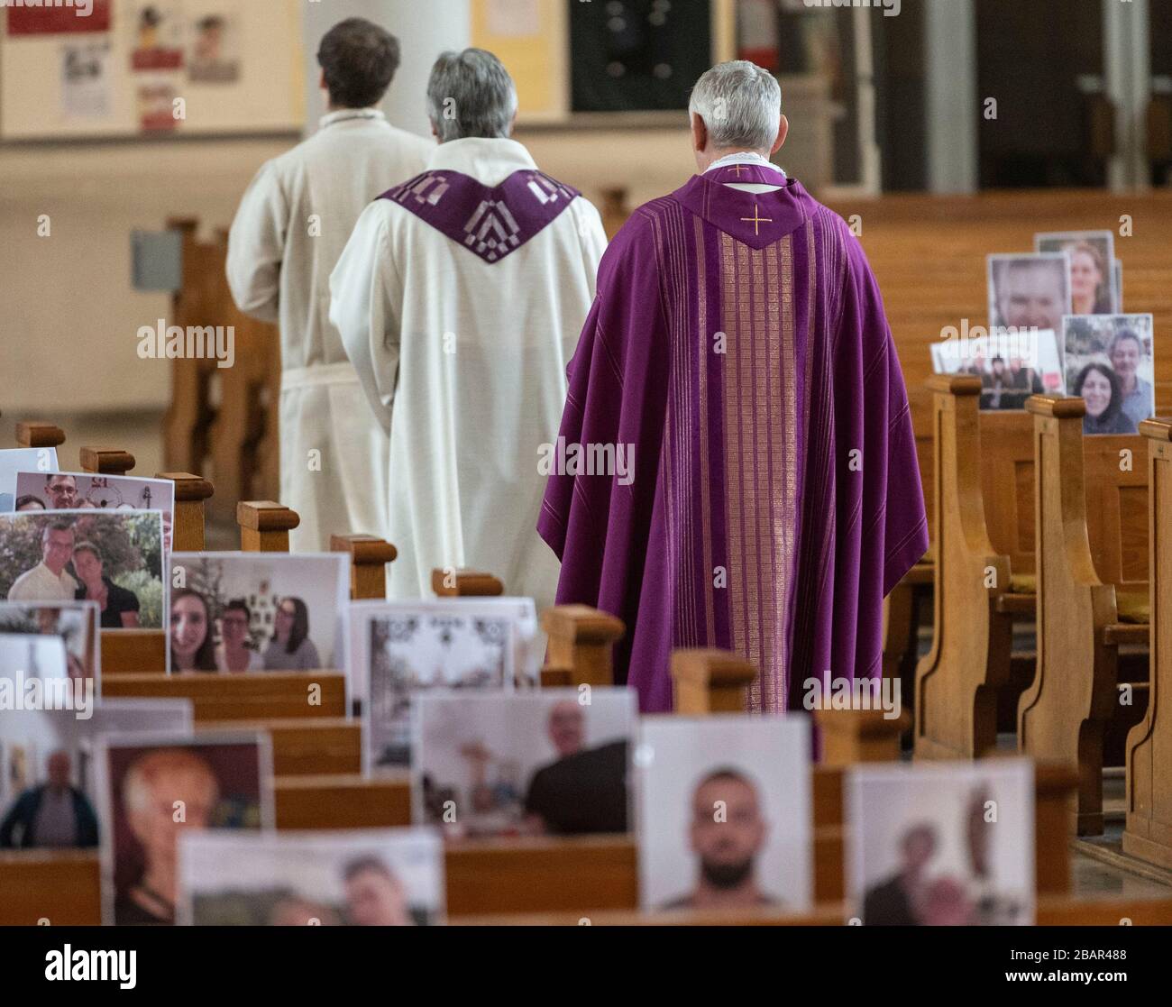 Achern, Germany. 29th Mar, 2020. Priest Joachim Giesler (h) walks past photos with parishioners in the parish church. Church services take place in front of empty churches due to the coronavirus. The parish had asked its parishioners to send pictures. More than 300 pictures were printed out and hung on the pews. Credit: Patrick Seeger/dpa/Alamy Live News Stock Photo