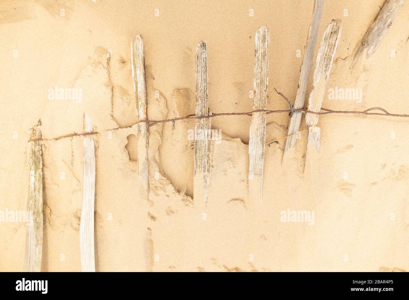 Close up of part buried wooden fence on sandy beach , Formby, England,UK Stock Photo