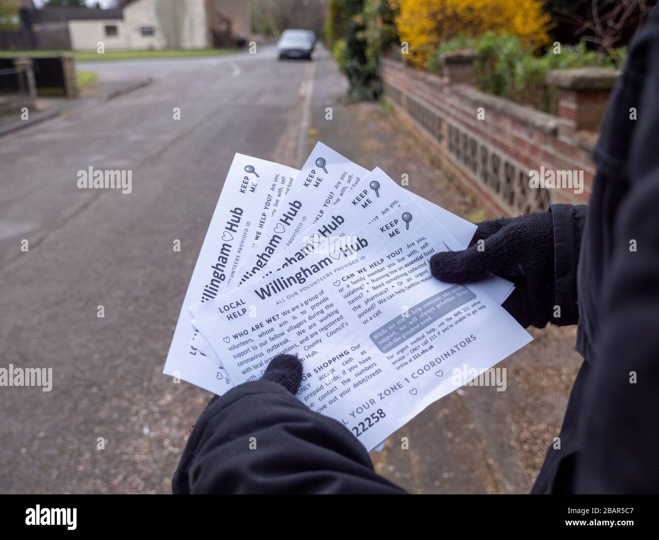 Willingham, Cambridgeshire, UK. 29th Mar, 2020. A volunteer delivers leaflets to houses in the village explaining the local support available to help people in the coronavirus pandemic. The Willingham Hub has been set up by local volunteers to provide support to people during the Covid-19 virus outbreak. Credit: Julian Eales/Alamy Live News Stock Photo