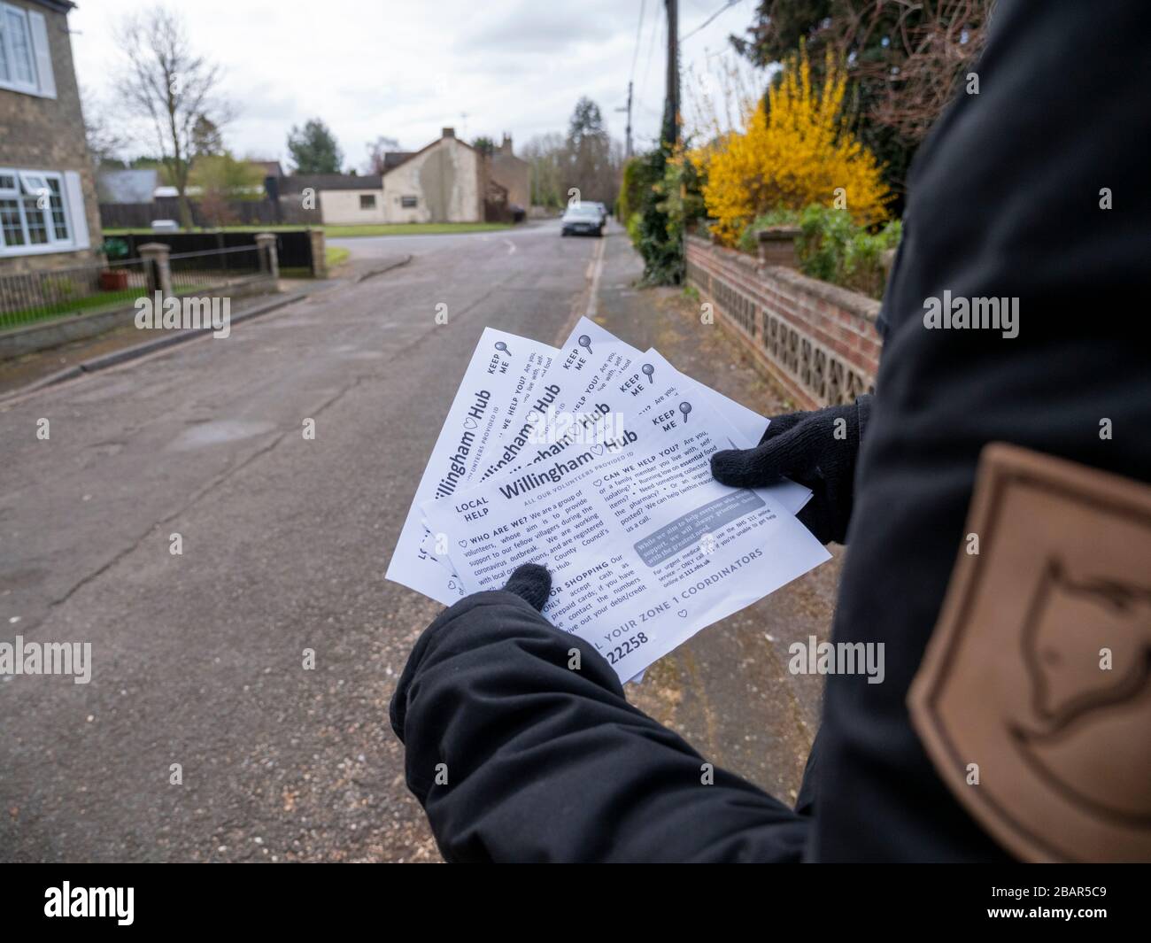 Willingham, Cambridgeshire, UK. 29th Mar, 2020. A volunteer delivers leaflets to houses in the village explaining the local support available to help people in the coronavirus pandemic. The Willingham Hub has been set up by local volunteers to provide support to people during the Covid-19 virus outbreak. Credit: Julian Eales/Alamy Live News Stock Photo