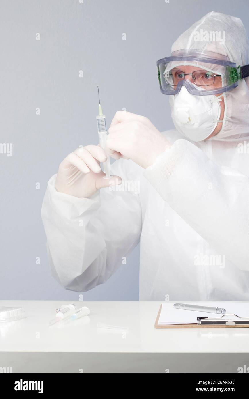 Doctor with surgical mask preparing a syringe with a vaccine against coronavirus Stock Photo