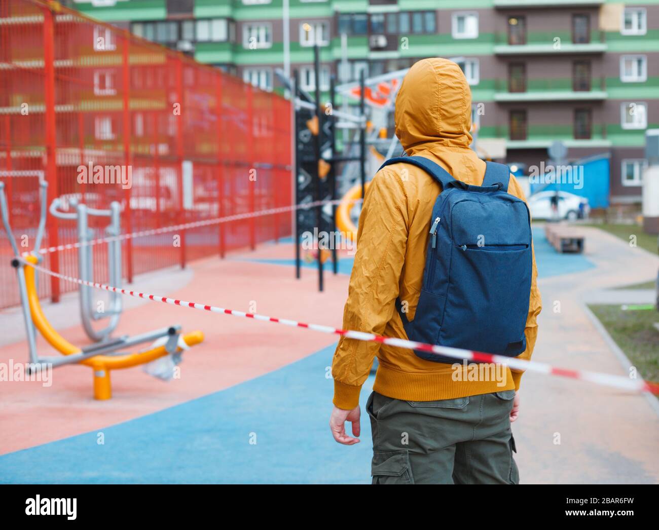 Man standing in front of fenced outdoor gym. Coronavirus or covid 19 quarantine Stock Photo
