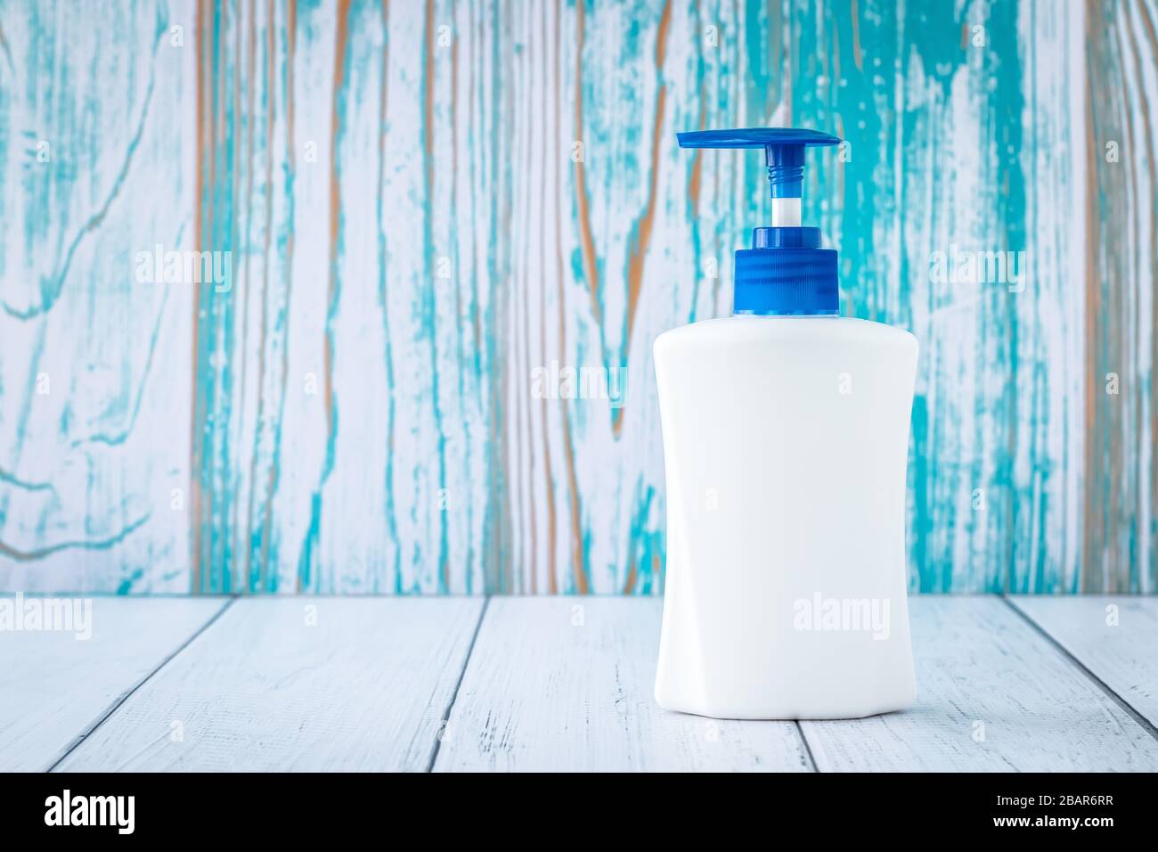 Antibacterial liquid soap with dispenser in bathroom. Disinfection concept. Protection from flu viruses, sanitizer, gel in white bottle on blue wooden Stock Photo