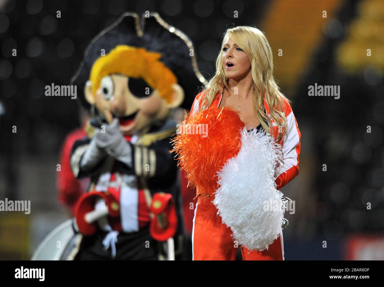 A Hooters cheerleader before the game as Sheffield United mascot Captain Blade looks on behind Stock Photo