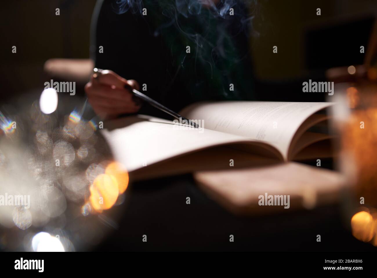 Fortune teller with open book of predictions on table with candles, close-up Stock Photo