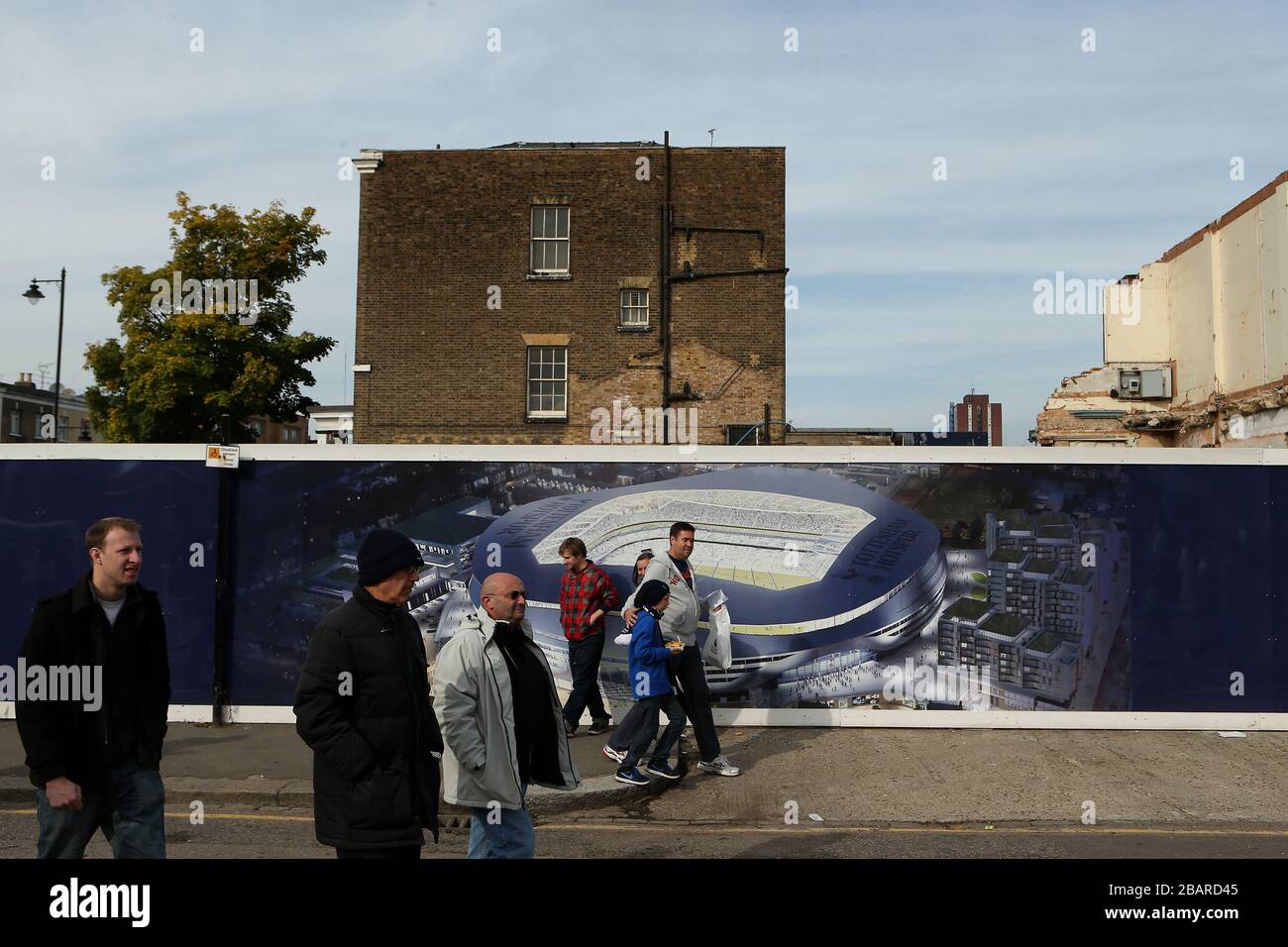 Fans walk past hoardings displaying an artists impression of the clubs' plans for a new stadium to be built next to White Hart Lane Stock Photo