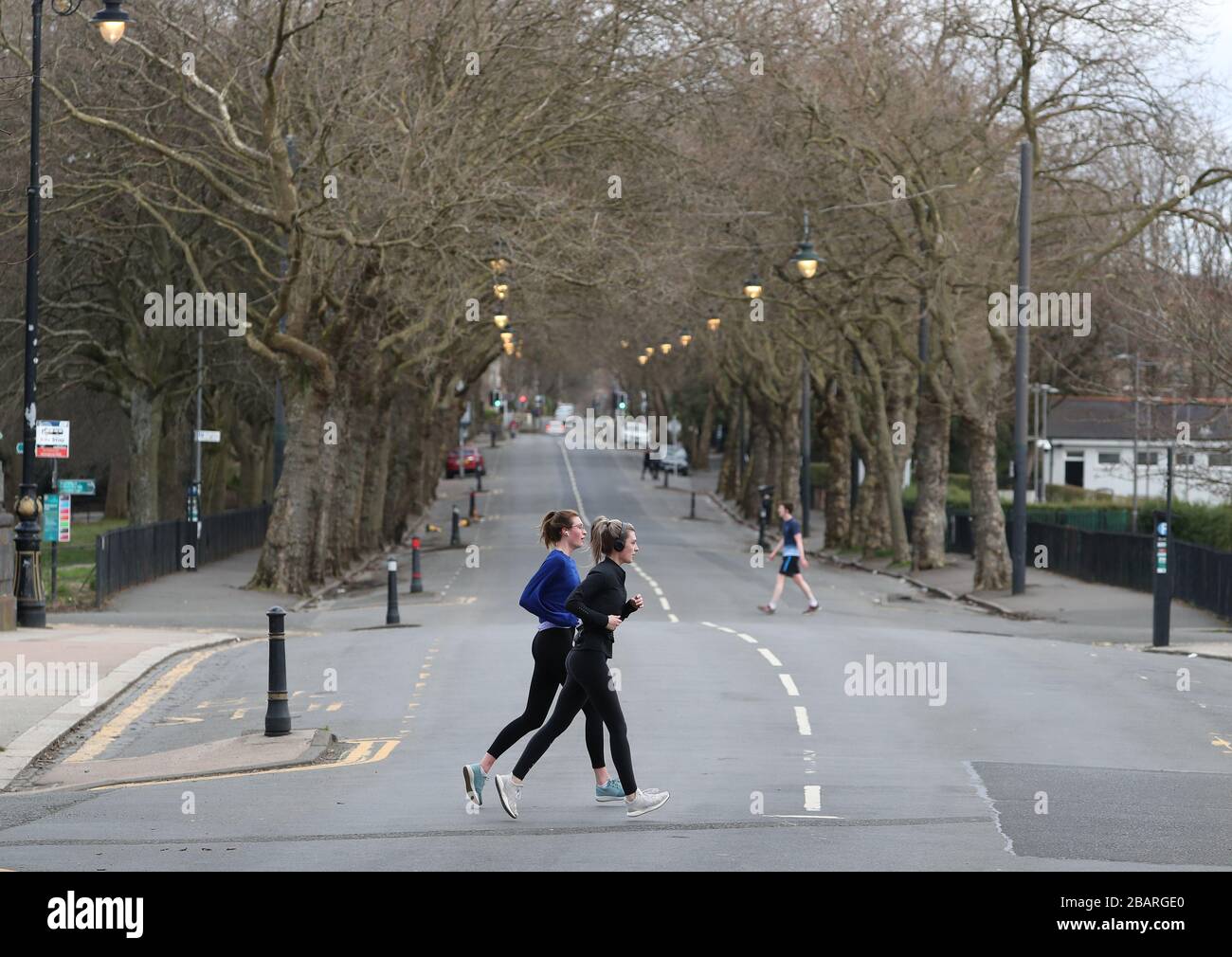 Joggers cross Kelvin Way in Glasgow as the UK continues in lockdown to help curb the spread of the coronavirus. Stock Photo