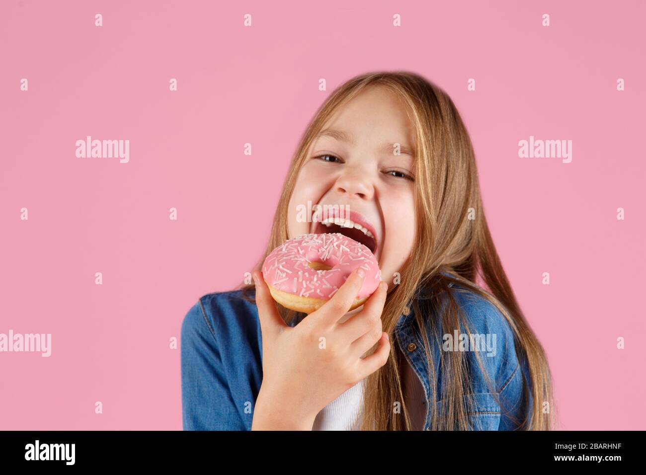 girl playing with a donut on a pink background Stock Photo