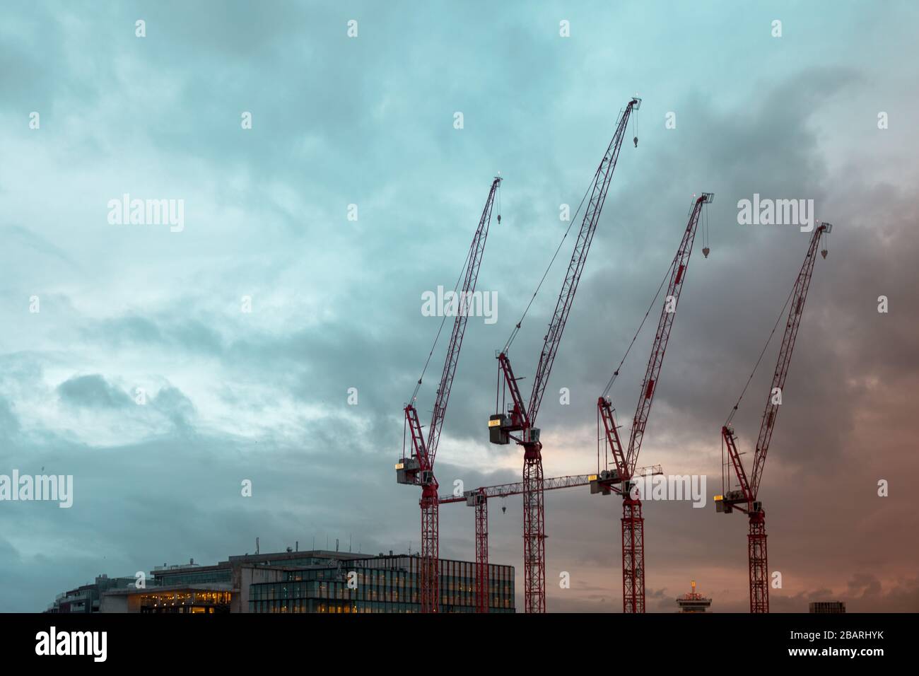 Low angle shot of construction cranes under a cloudy sky in Amsterdam ...