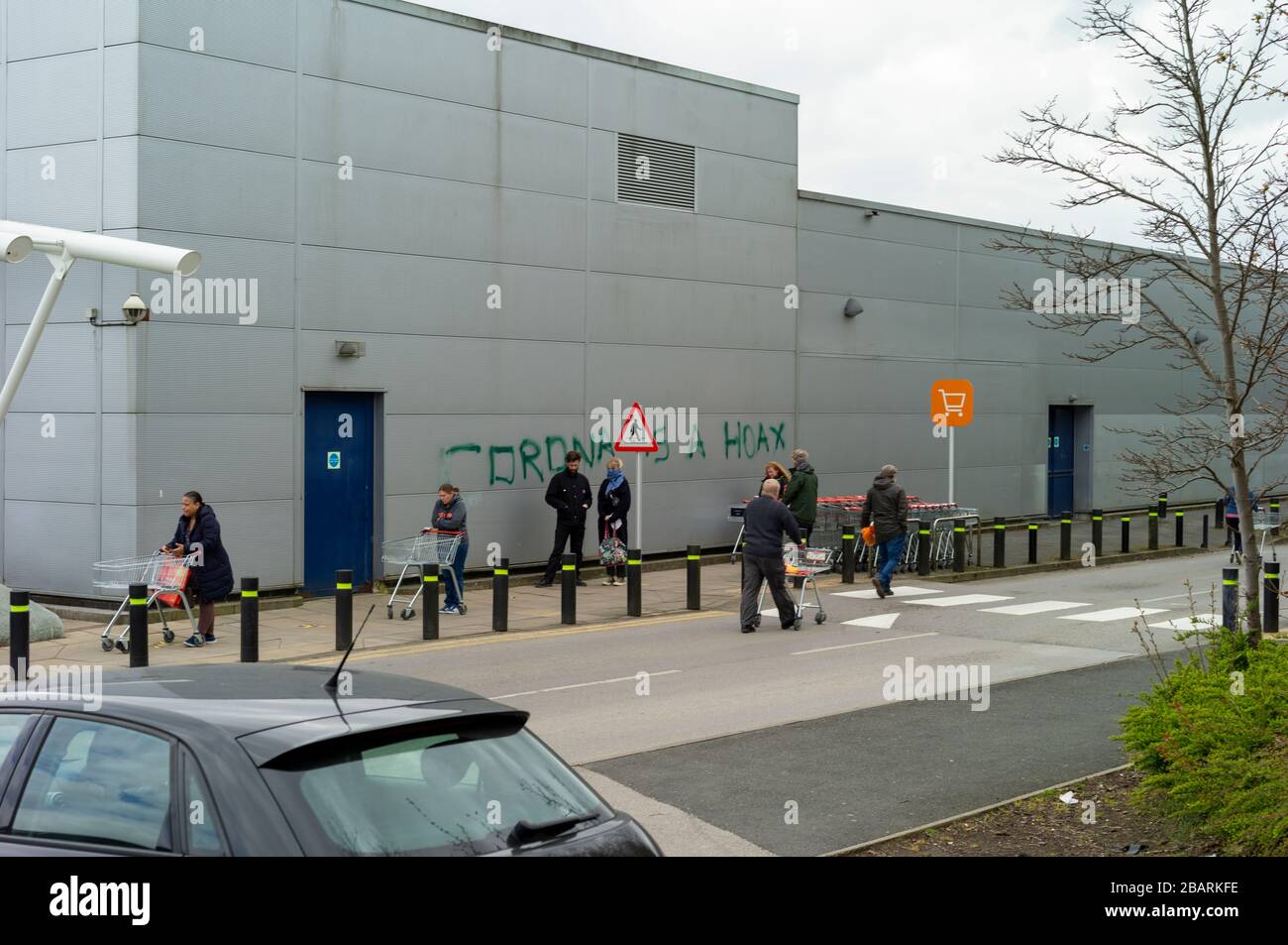 Leeds, West Yorkshire, UK. Sunday 29 March 2020. Covid-19 / Corona Hoax Graffiti, Sainsbury's Supermarket, Moor Alleron Leeds LS17 'social distancing' queue 2pm. Credit: © Garry Clarkson/BMT/Alamy Live News Stock Photo