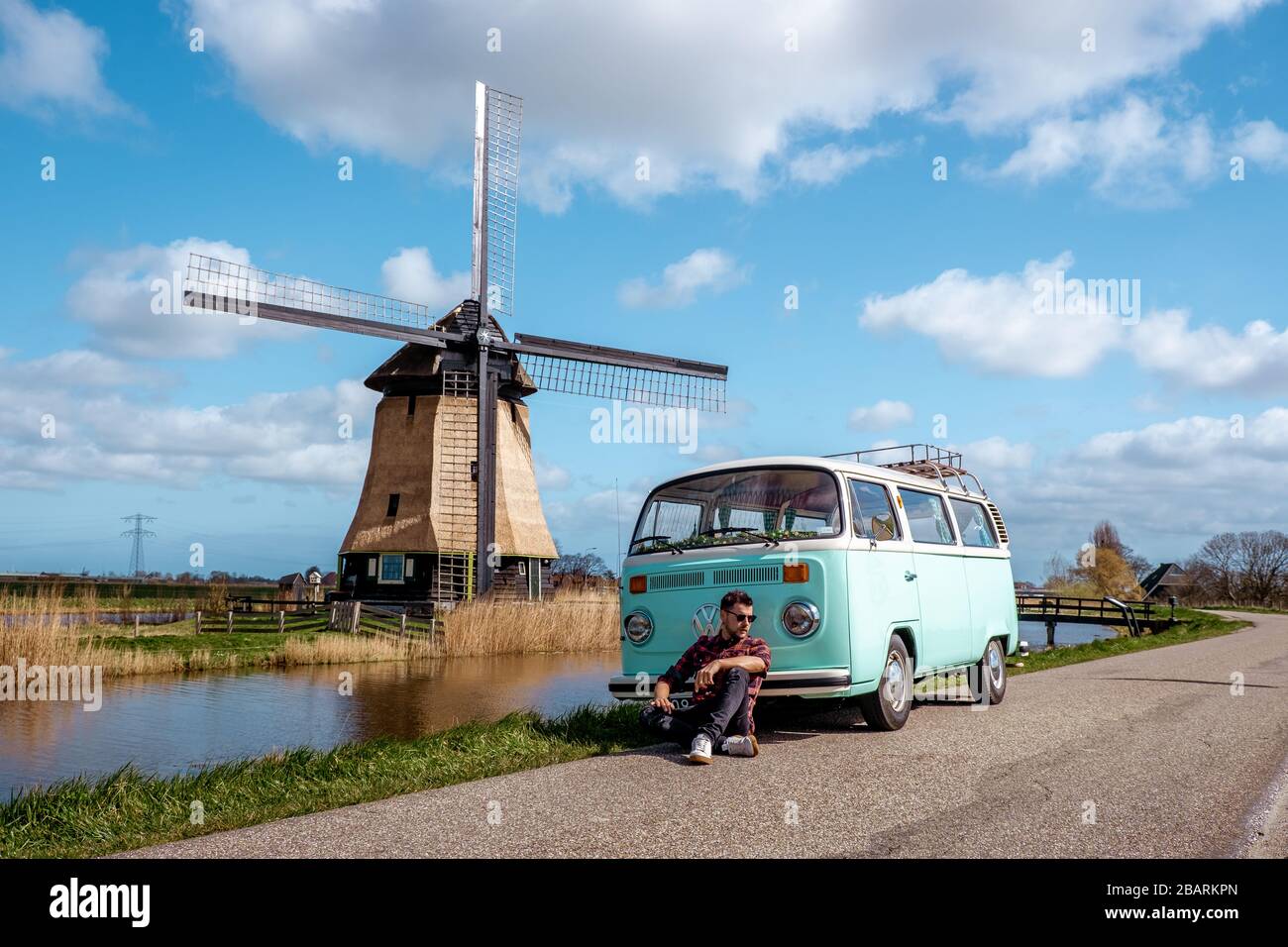 Alkmaar Netherlands April 2019, classic old vintage car van parked by historical windmill in Holland, Classic Minty Green and white VW Camper Van Stock Photo