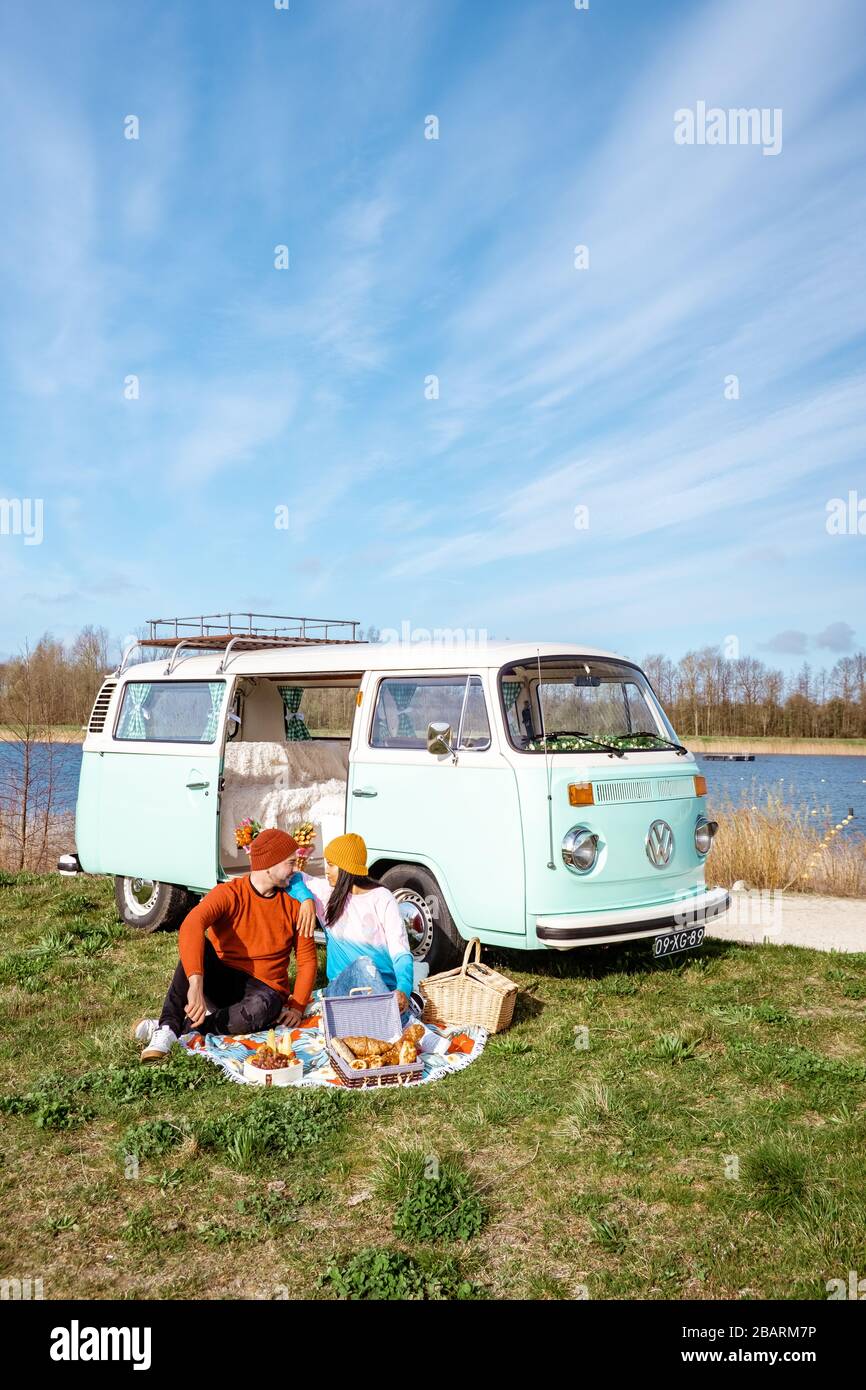Noordoostpolder Netherlands April 2019, Classic Green and white VW Camper Van parked with couple watching the Sunrise over the meadow during Spring Stock Photo