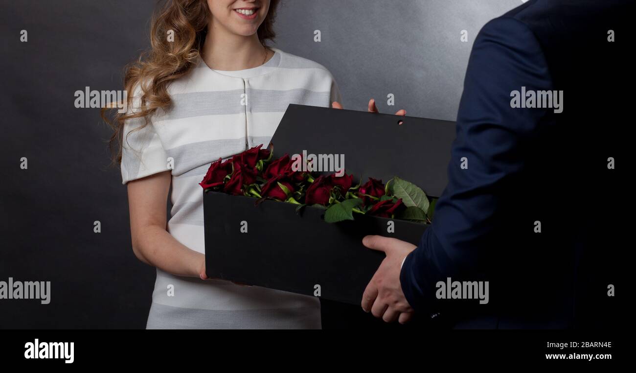 man gives red roses in an original box to his beloved woman Stock Photo ...