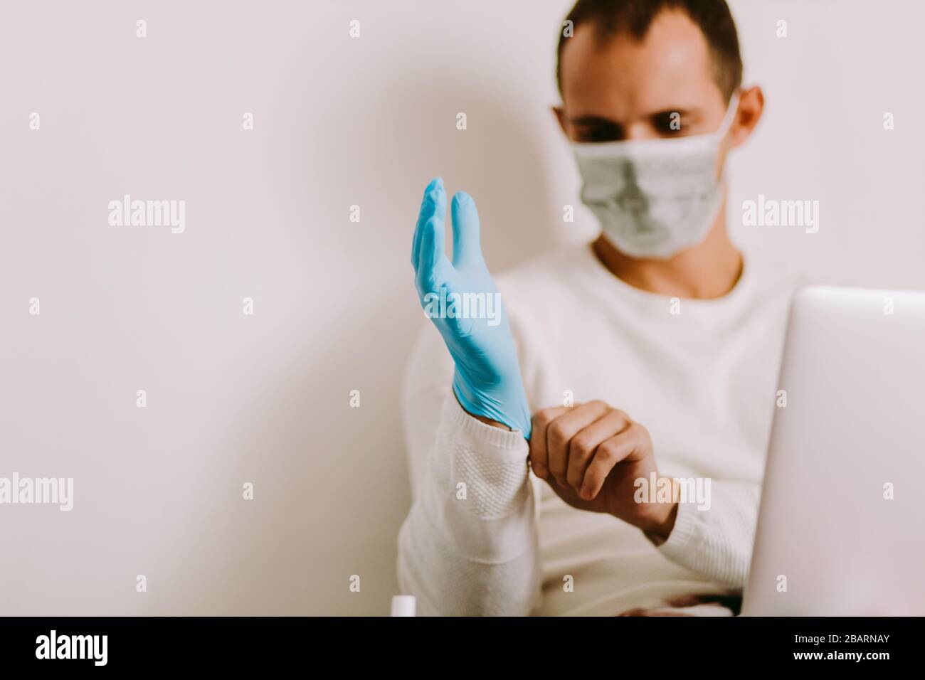 Man Wearing Latex Gloves and face mask indoors. Caucasian male using
