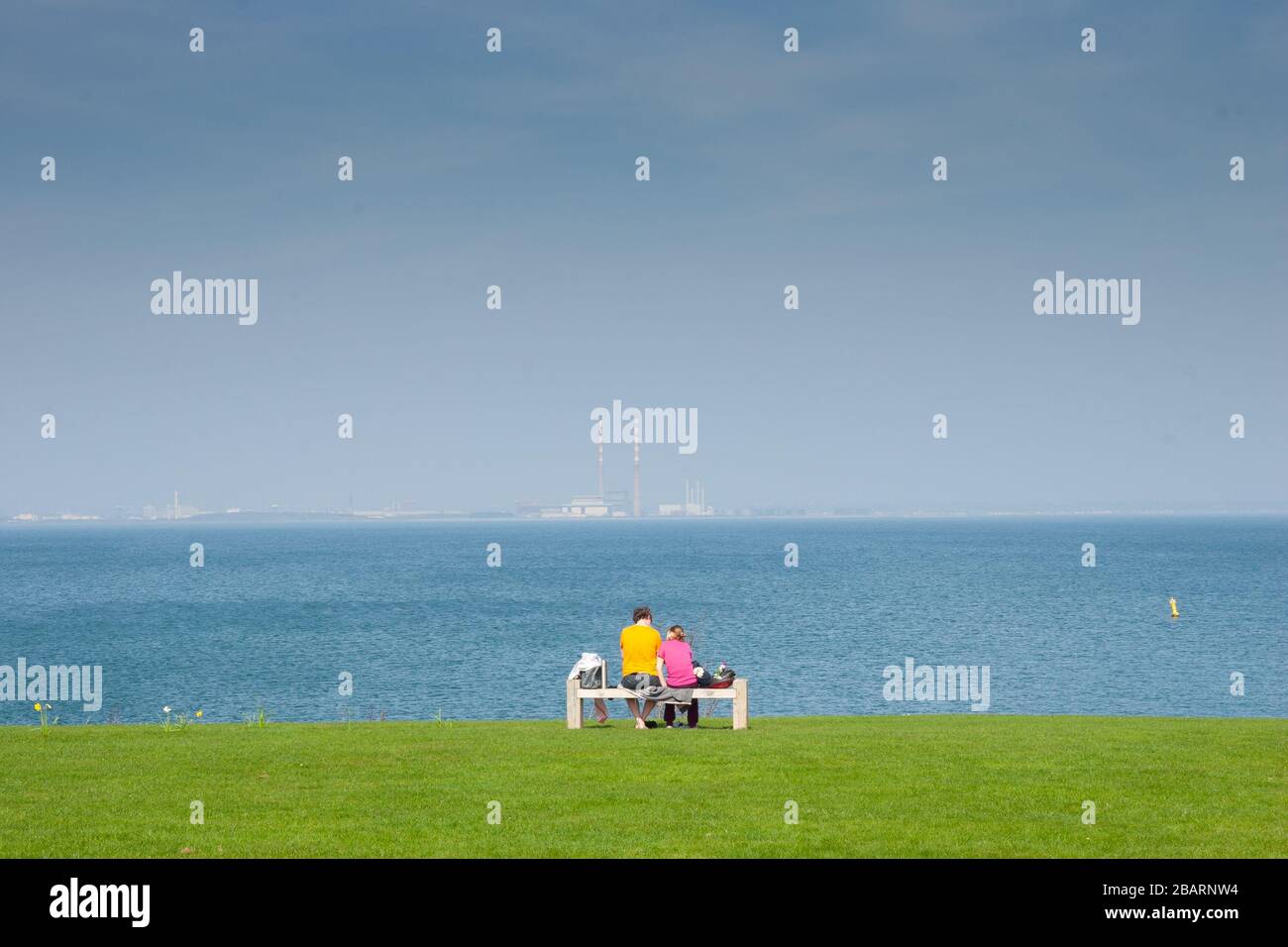 Couple sitting on bench together at the beach in love Stock Photo - Alamy
