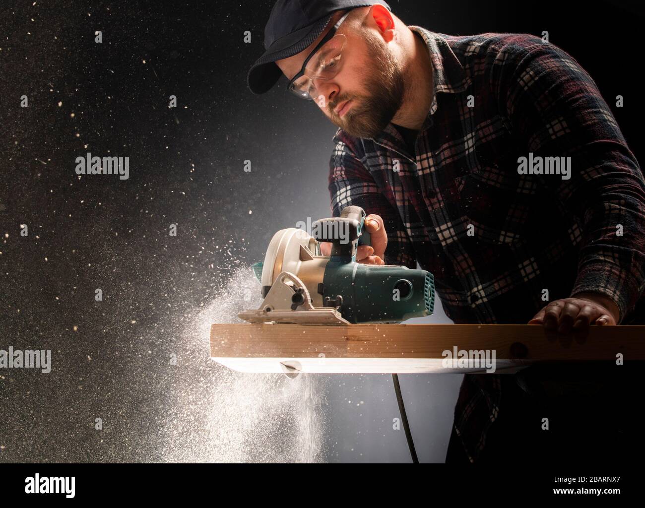 Construction worker crosses a board with a circular saw. Stock Photo