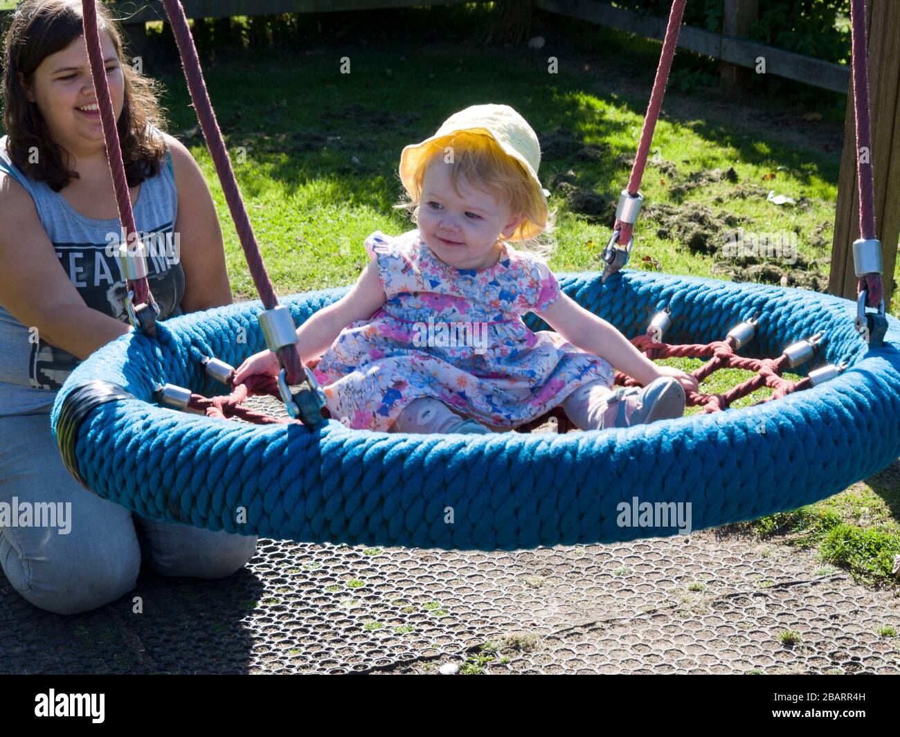 Mum and daughter playing on a swing, UK Stock Photo