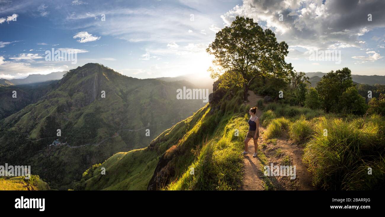 Girl standing on the summit of Little Adam's Peak at sunset in Ella, Sri Lanka Stock Photo