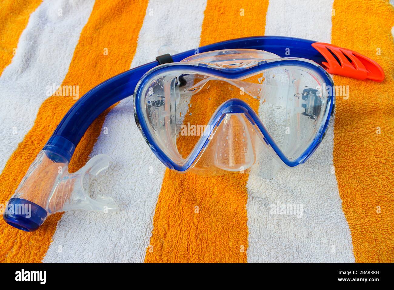 Snorkel and diving mask on a white and yellow striped towel Stock Photo ...