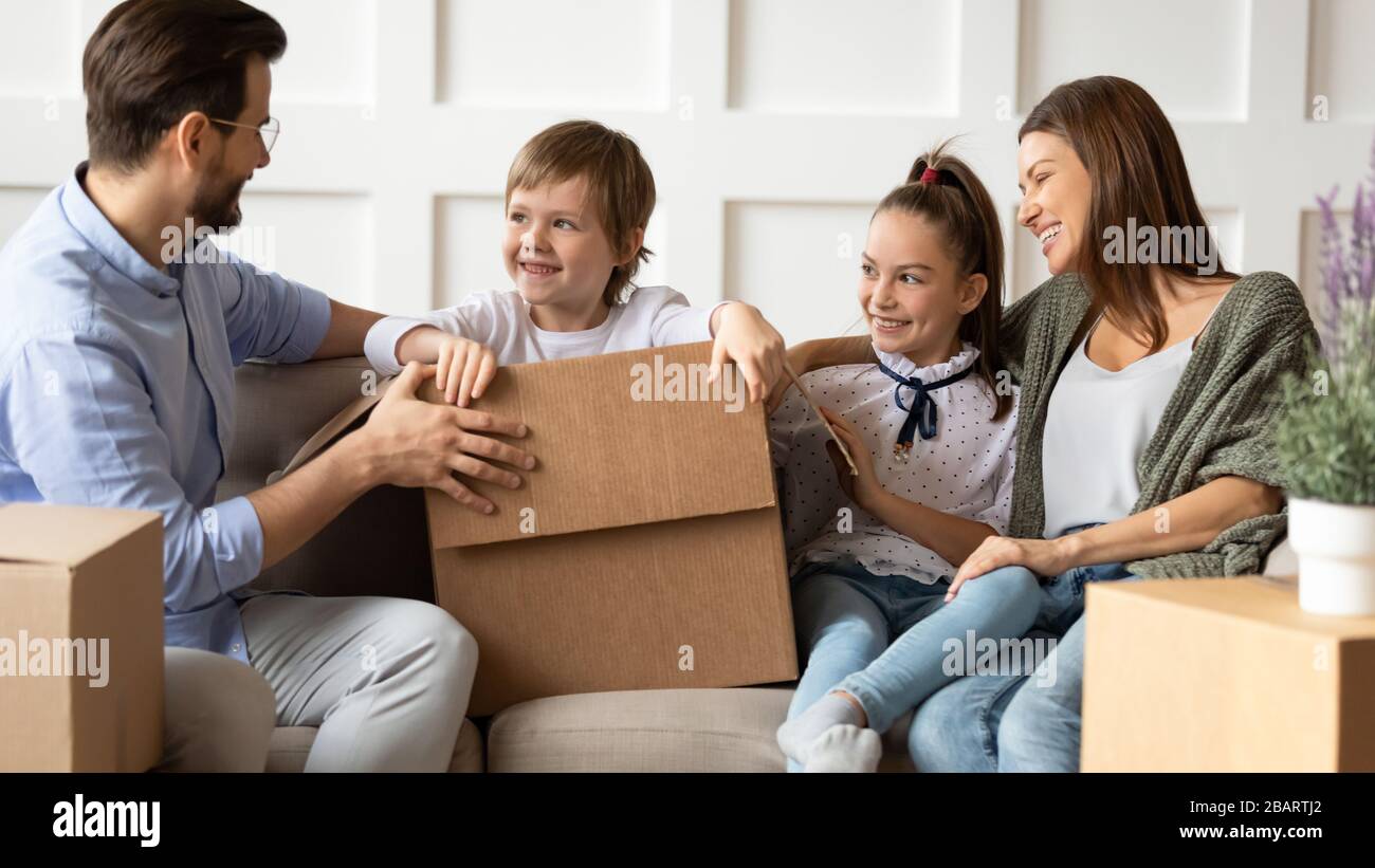 Smiling couple having fun with children after moving in apartment. Stock Photo