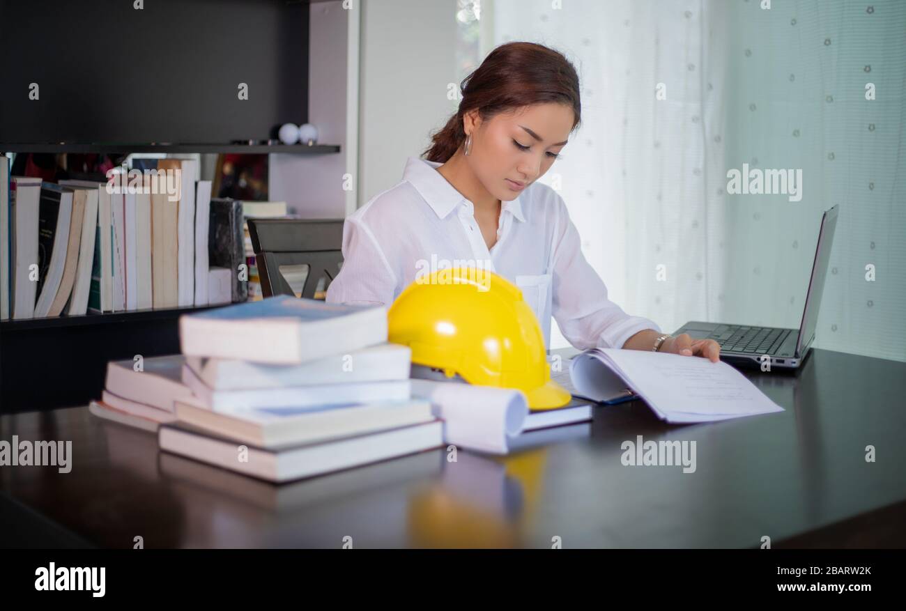 Beautiful Asian engineering women checking document and using notebook ...
