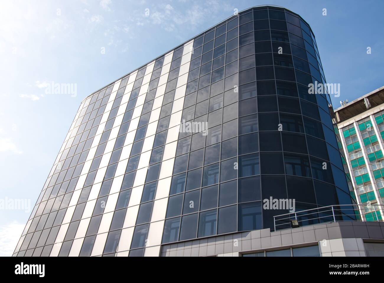 Kharkiv, Ukraine, March 29, 2020: Modern office building with reflection in windows of blue sky. Dark high-rise skyscraper of glass. Facade of office Stock Photo