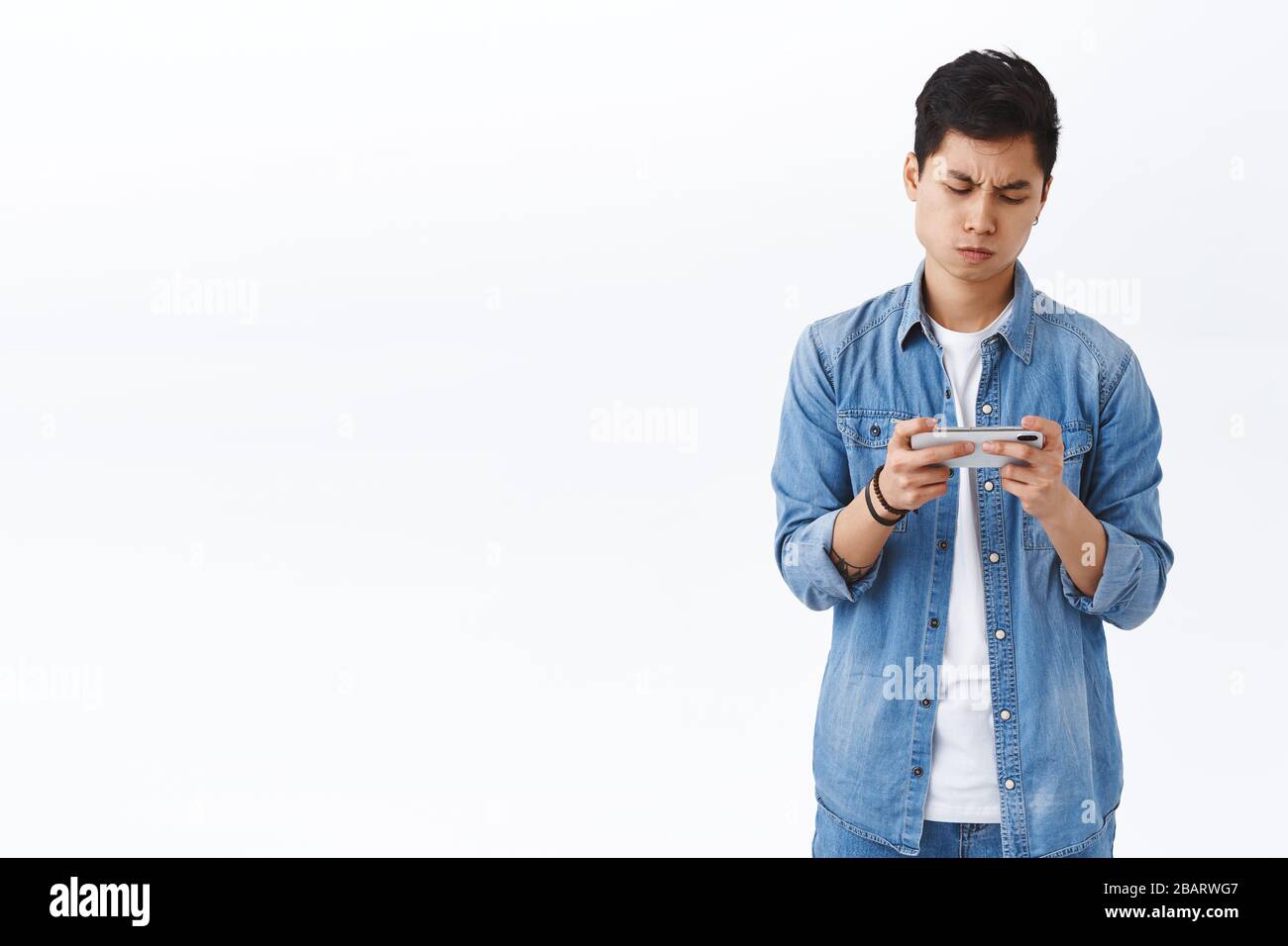 Technology, online lifestyle concept. Portrait of bothered and annoyed, young gloomy asian guy cant win in game, look upset losing level, holding Stock Photo
