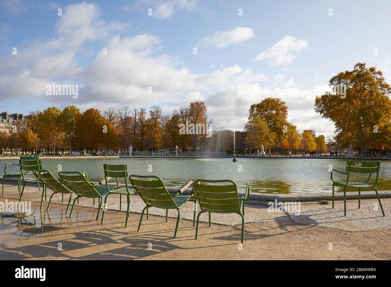 PARIS - NOVEMBER 7, 2019: Tuileries garden with green metal chairs and fountain in a sunny autumn day in Paris Stock Photo