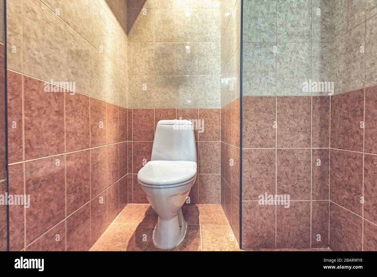 Toilet bowl in the toilet room. Restroom with beige tile decoration and  flooring Stock Photo - Alamy