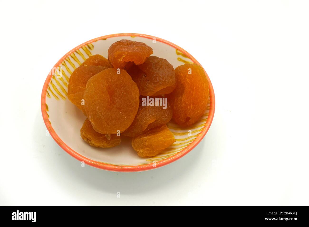 Dried apricots on a ceramic saucer isolated on white background. Energy