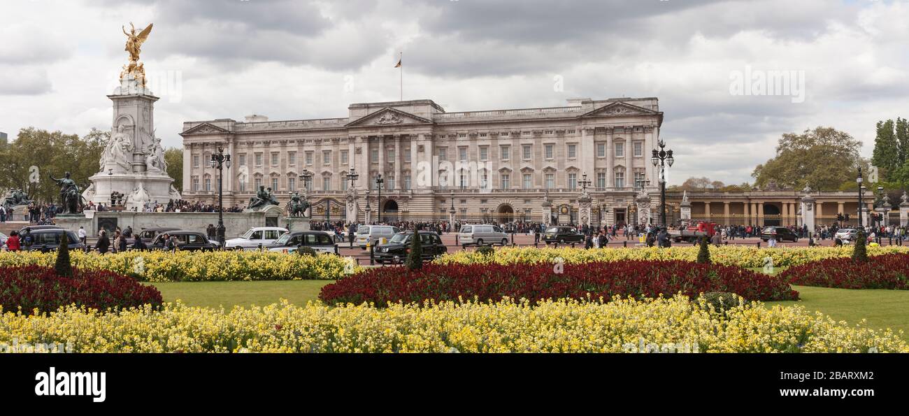 Buckingham Palace with gardens of the Victoria Memorial: The front facade of Buckingham Palace with the Victoria Memorial and spring flowers. Stock Photo