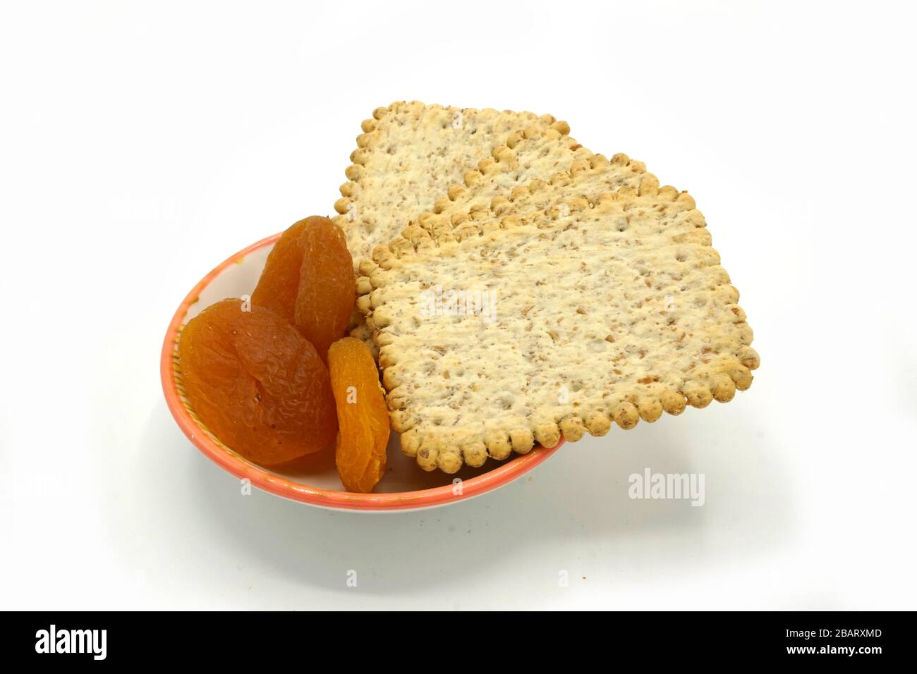 Dried fruits and digestive biscuits on a ceramic saucer isolated on