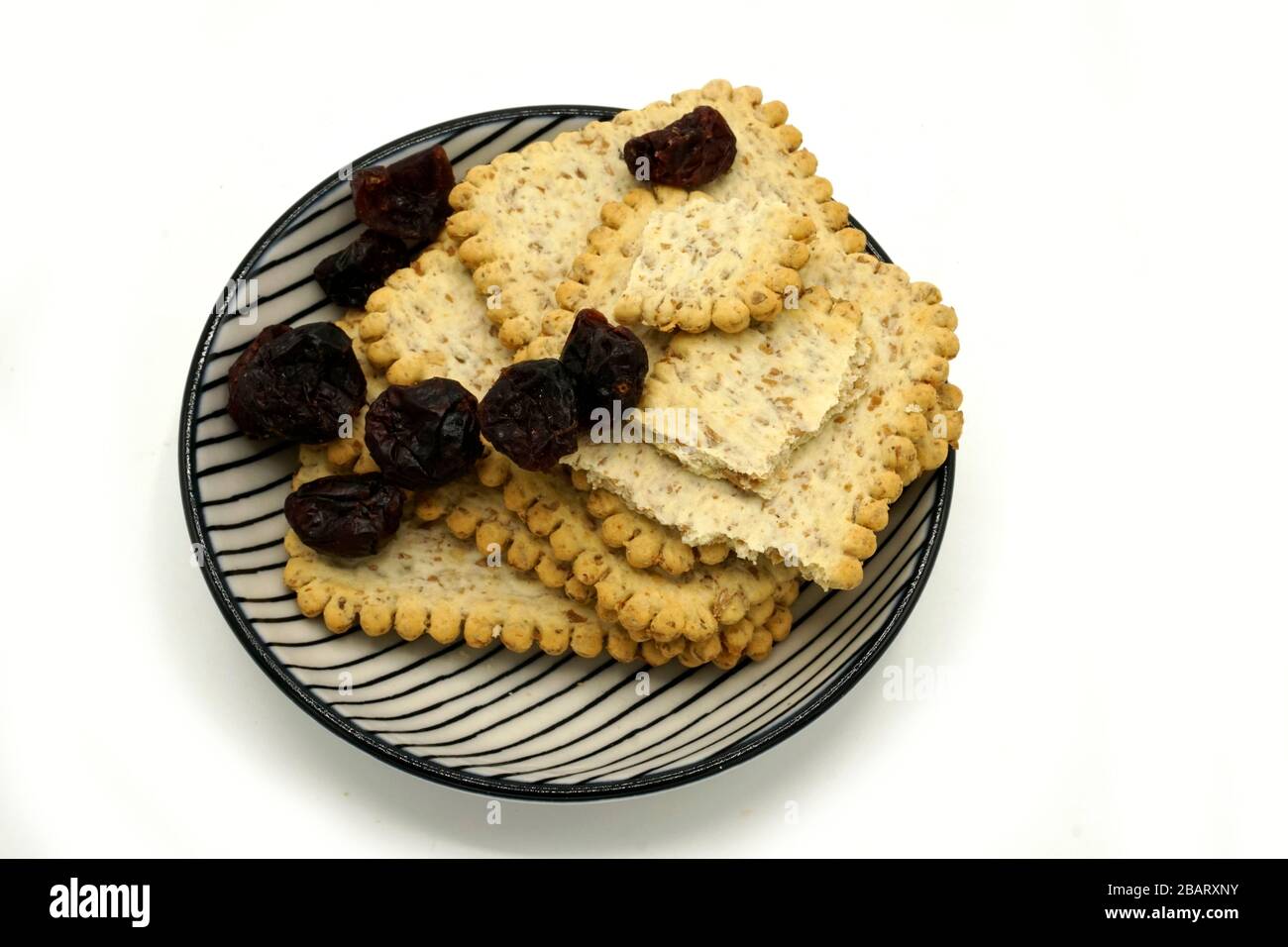 Dried fruits and digestive biscuits on a ceramic saucer isolated on