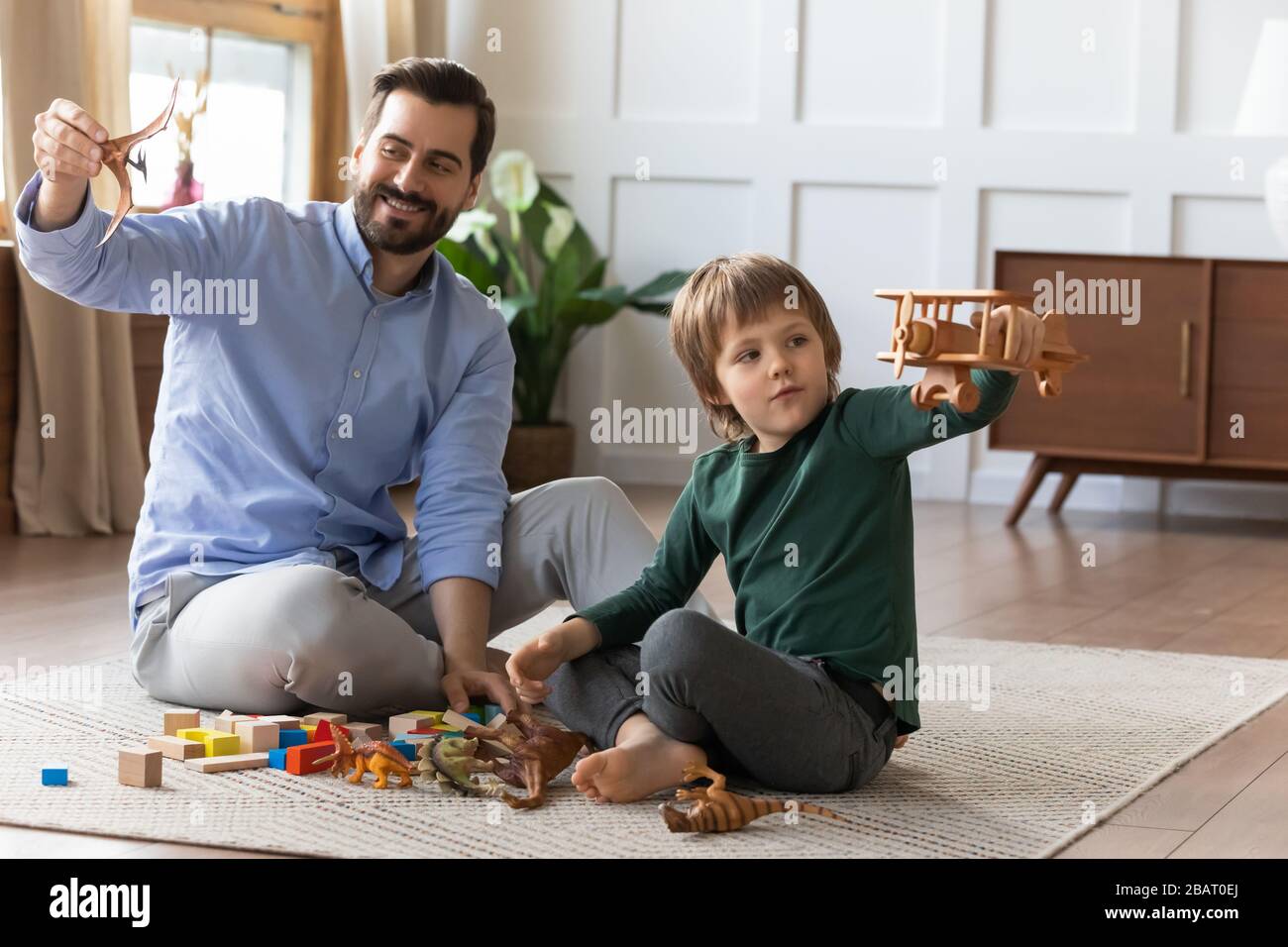 Little boy playing with wooden airplane, enjoying playtime with daddy. Stock Photo