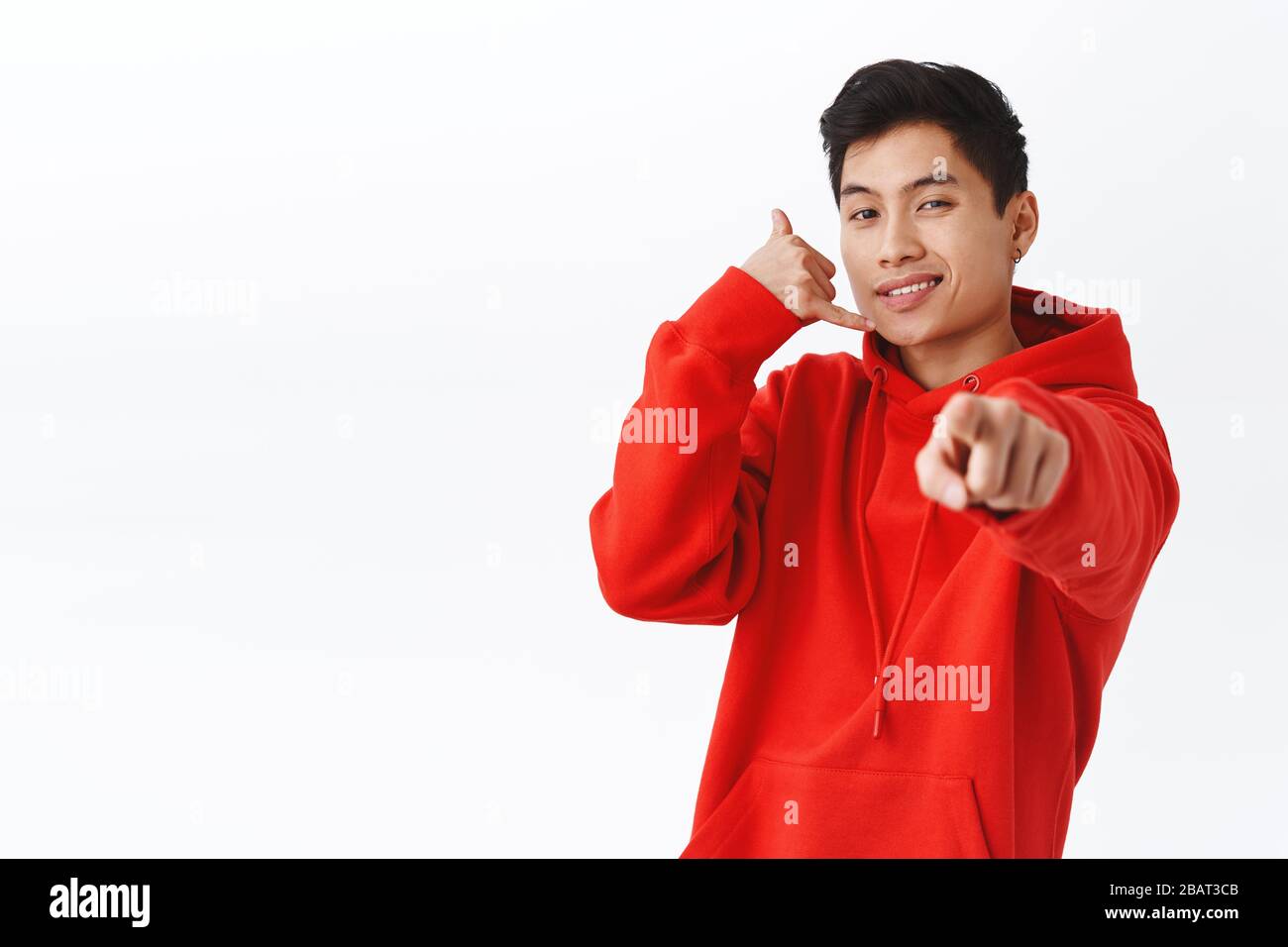 Call Me Maybe Portrait Of Cheeky Asian Man In Red Hoodie Pointing At Camera Smiling Sassy And Make Phone Gesture As If Asking Number Flirting With Stock Photo Alamy