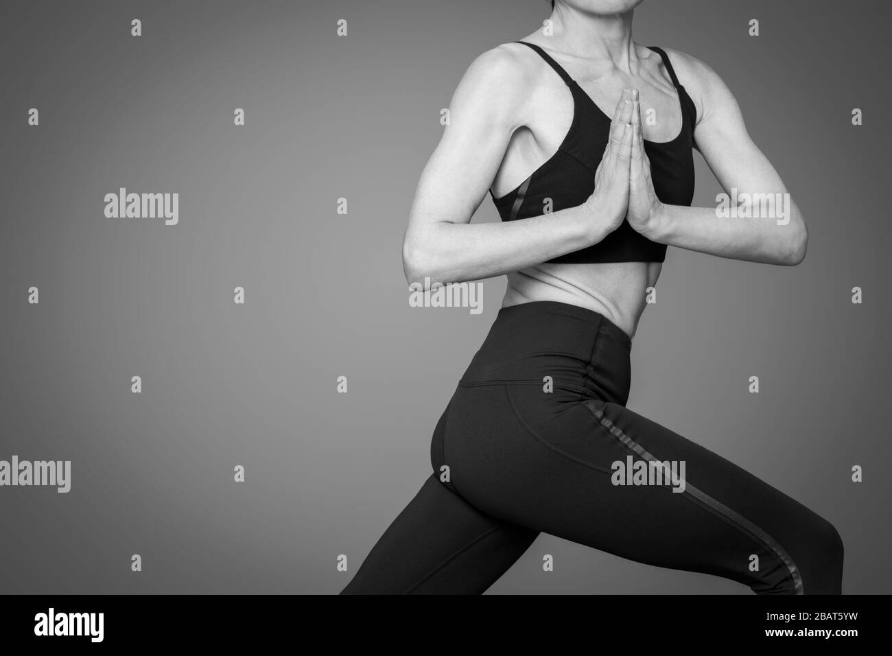 close up of a slim woman practicing yoga, warrior one pose with twist. Balck & white. Stock Photo