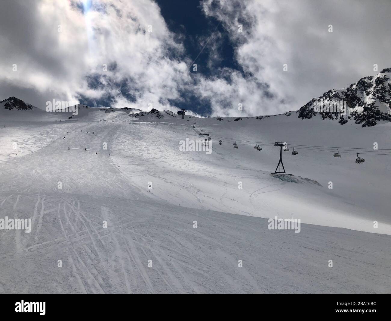 Panorama view of ski resort with slope, people on the ski lift, skiers on the piste among white snow Stock Photo
