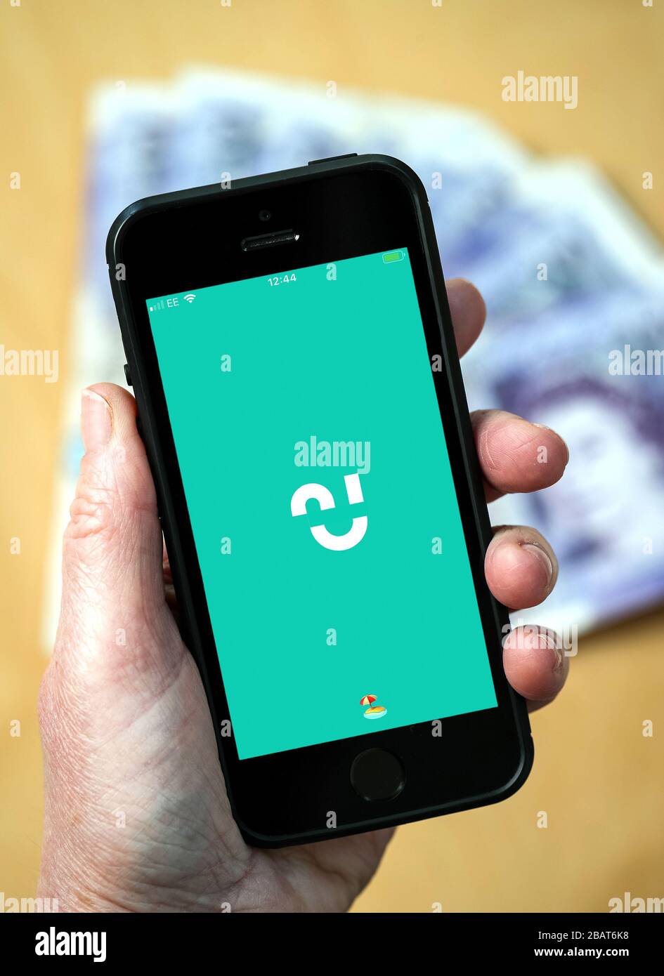 A woman using the Chip savings app on a mobile phone. (Editorial Use Only) Stock Photo