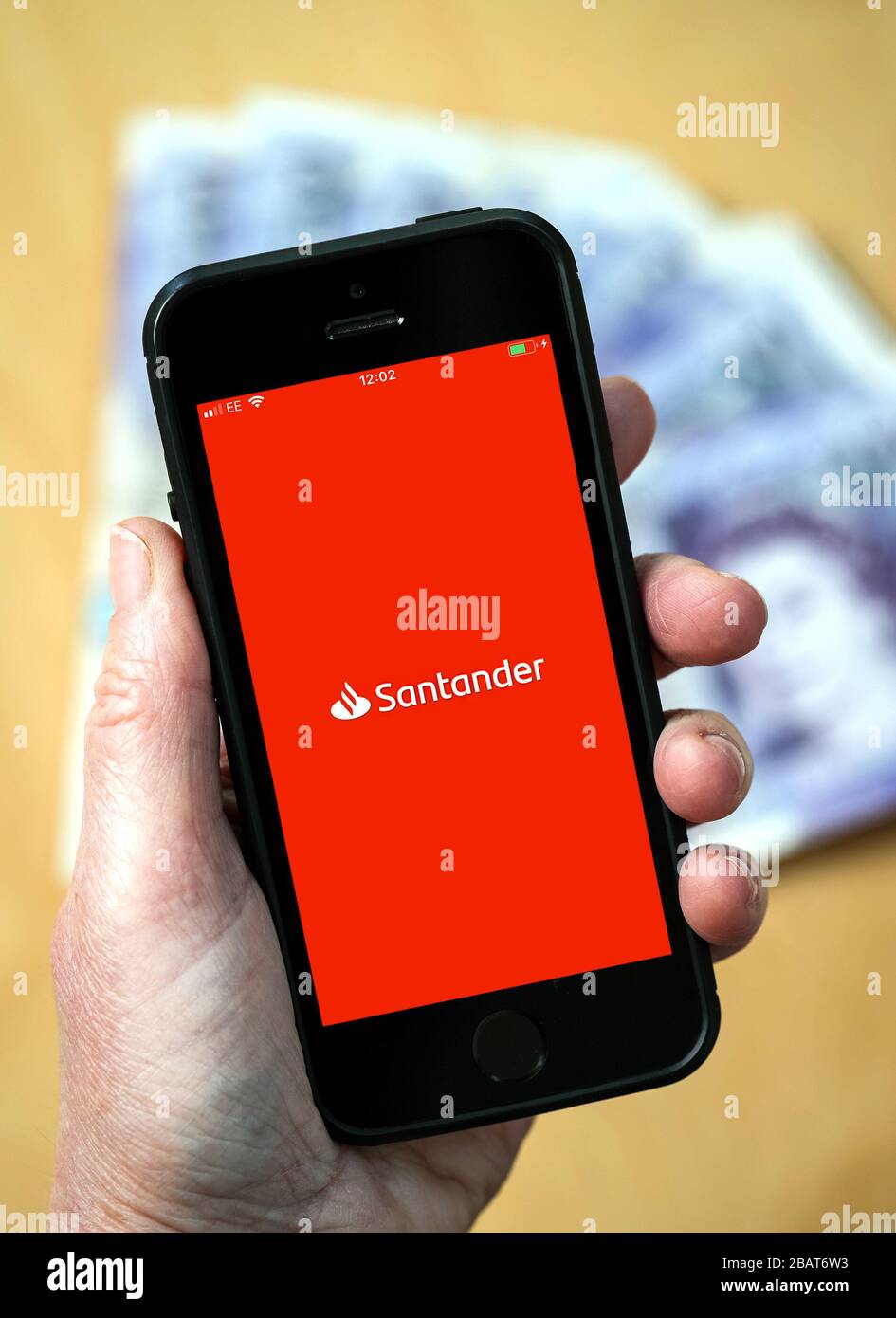 A woman using the Santander bank app on a mobile phone. (Editorial Use Only) Stock Photo