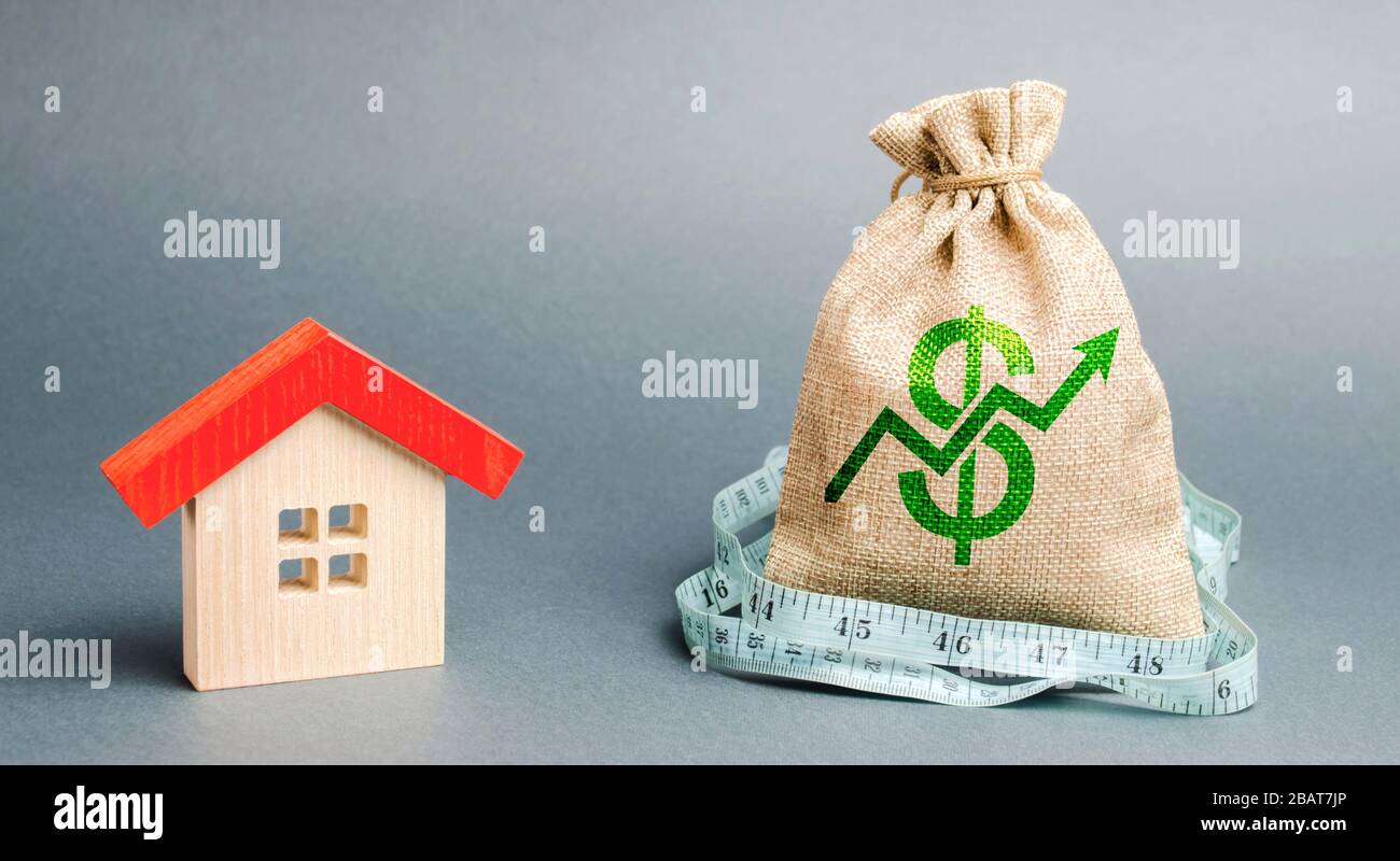 Wooden house and a money bag with arrow up. The concept of increasing the cost of housing. The growth of rent and mortgage rates. Raising rents, prope Stock Photo