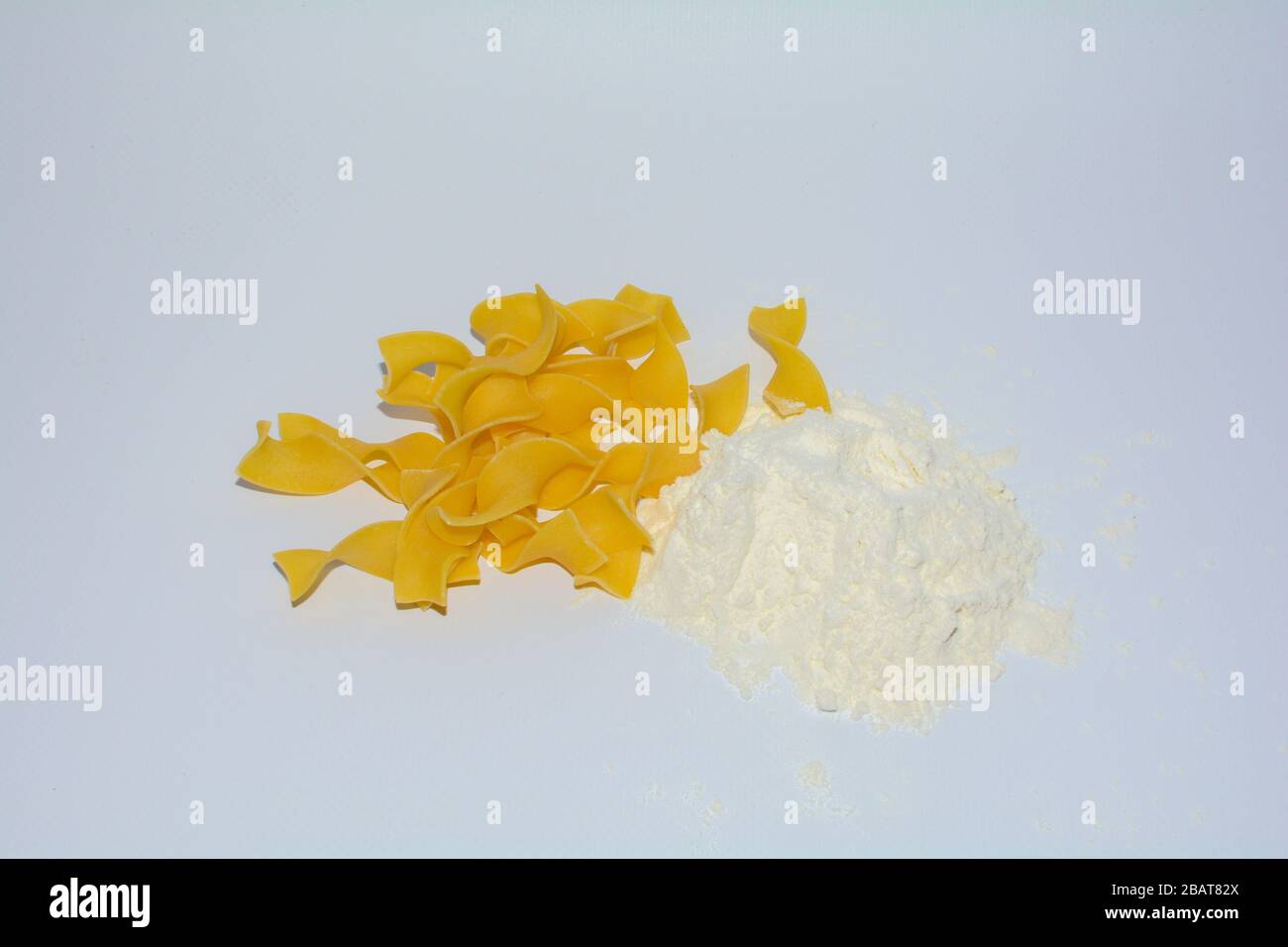 Yellow pasta and flour on white background with copy space Stock Photo