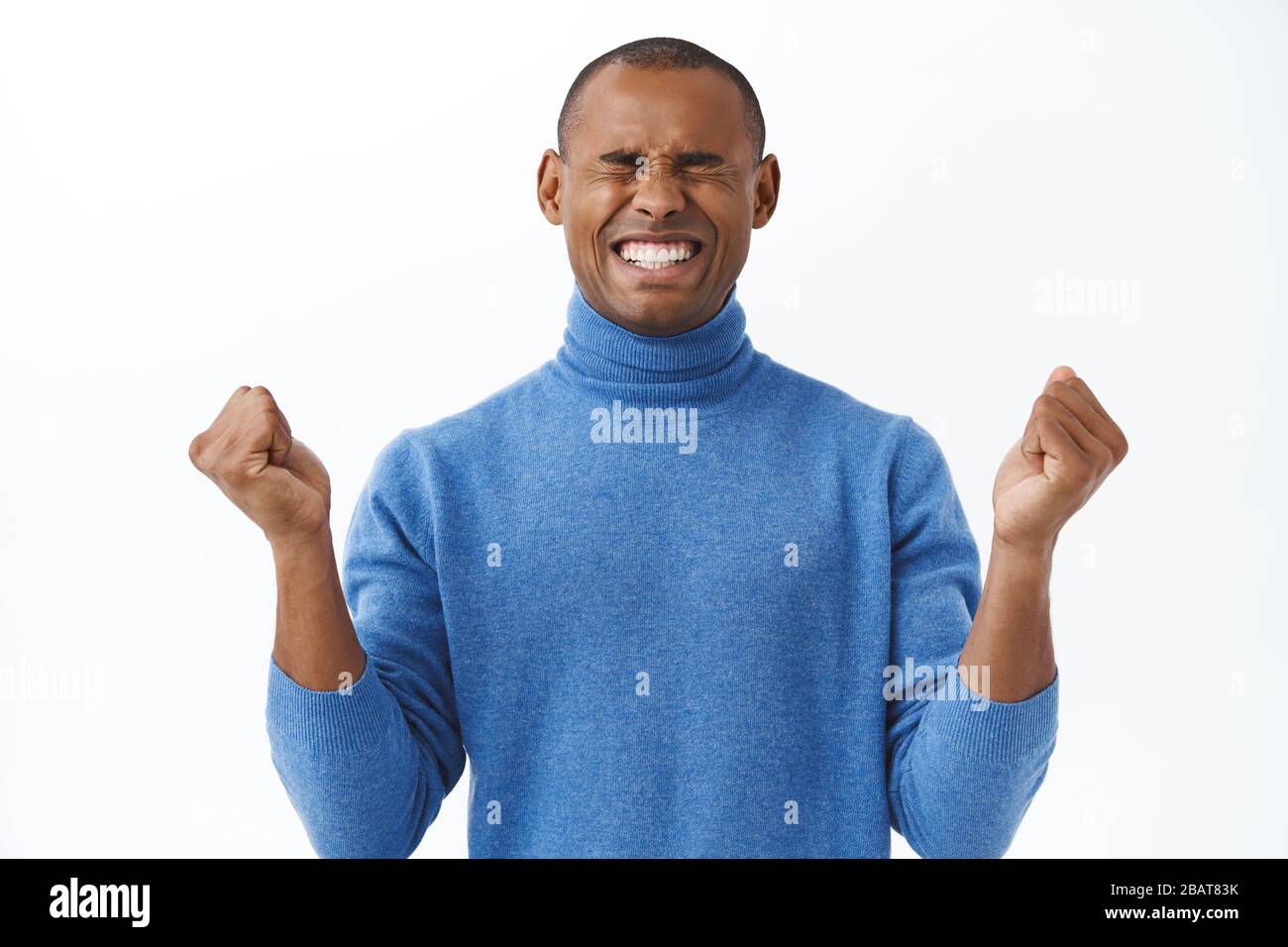 Portrait of encouraged young african american man boosting confidence, fist pump, close eyes and smiling, motivating himself stay positive, move on Stock Photo