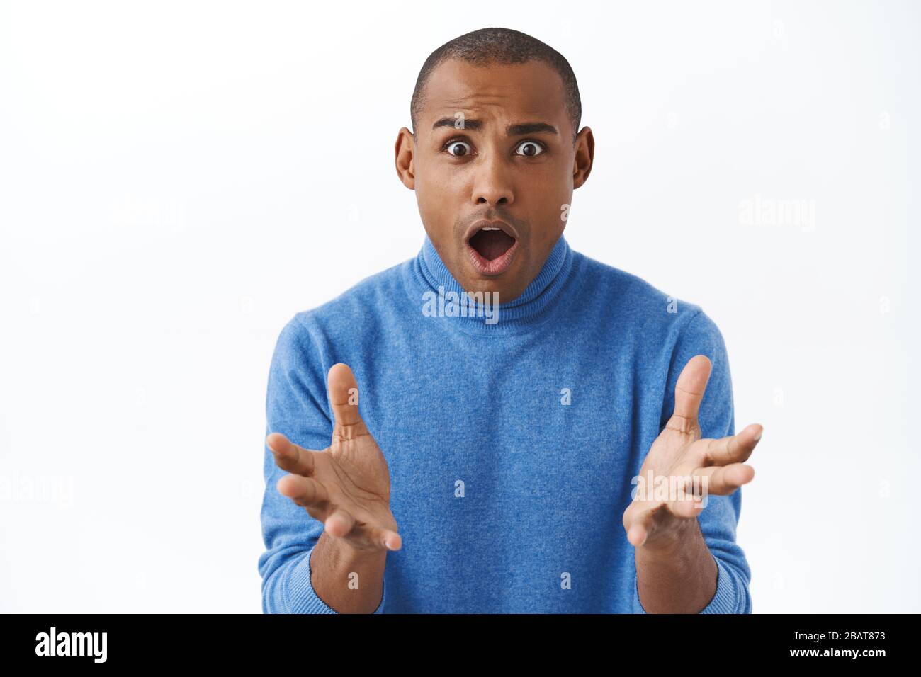 Close-up portrait of shocked, young frustrated african american adult man looking with desperate sad face at camera, raising hands in dismay, trying Stock Photo