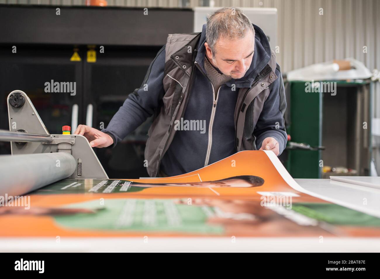 Worker printmaker technician operator works in large digital printing