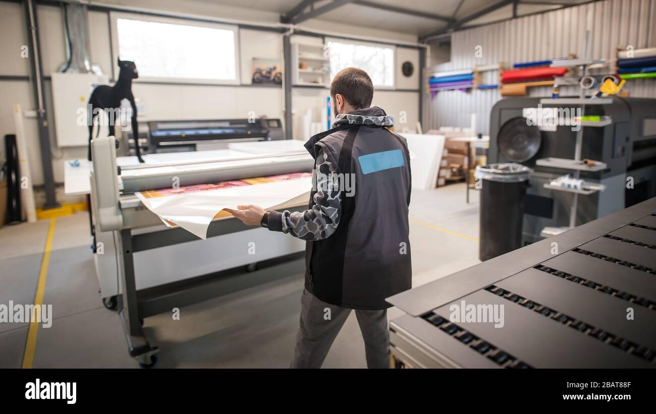 Worker printmaker technician operator works in large digital printing press  hall and printshop office with many different type of machine Stock Photo -  Alamy