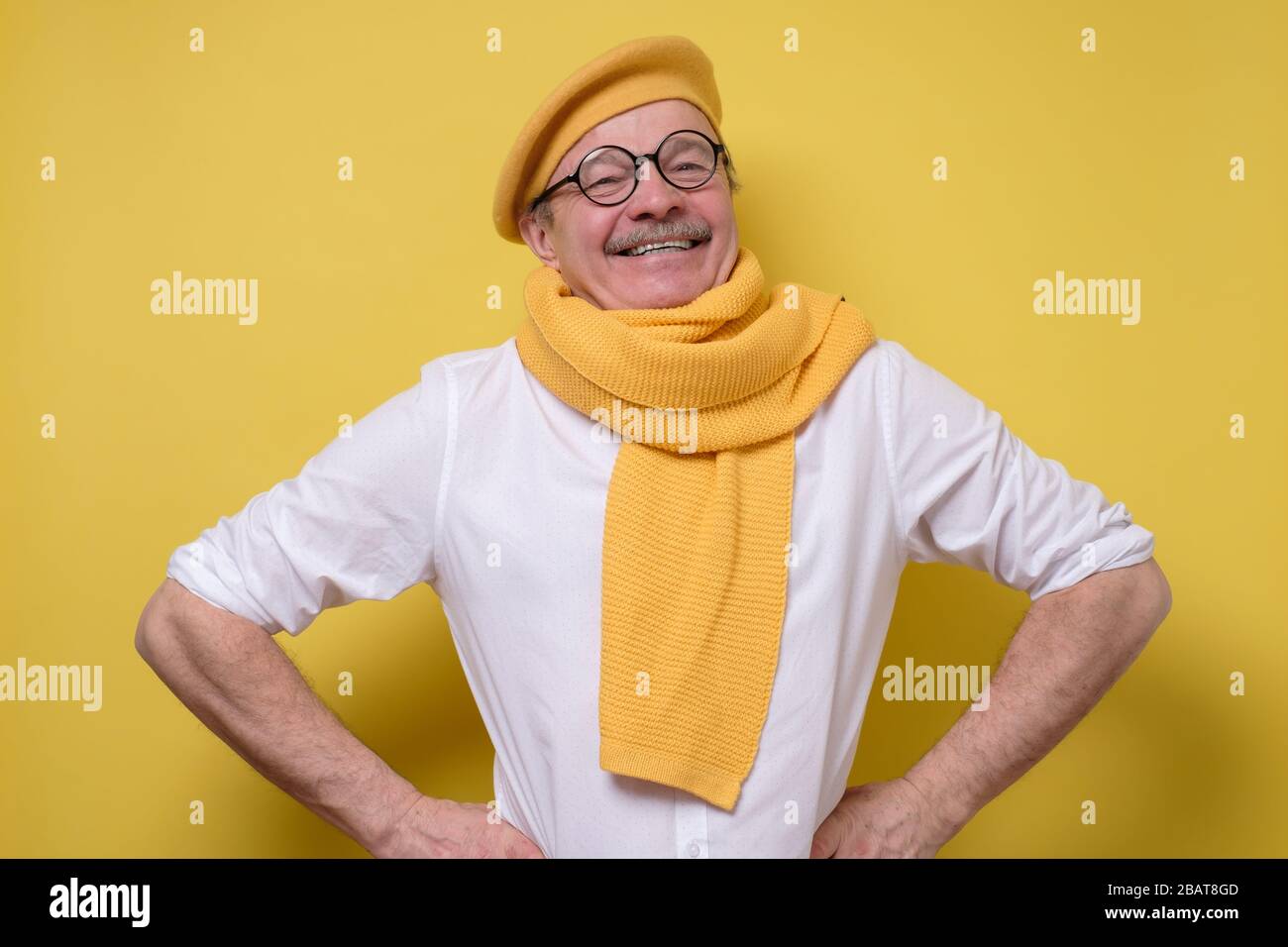 Senior handsome funny man in yellow scarf and hat and mustache feeling proud Stock Photo