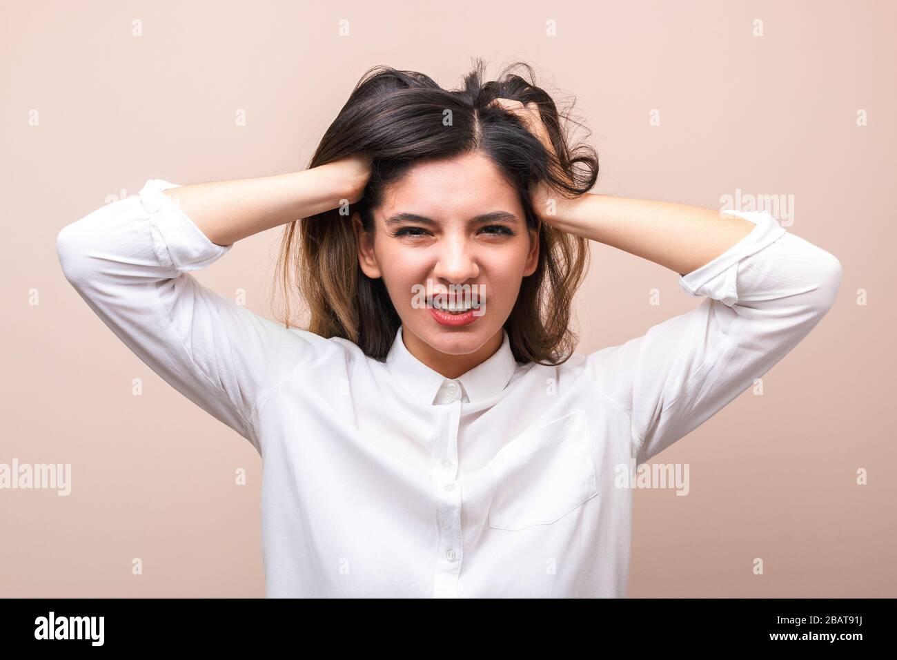 news influence. portrait of young annoyed businesswoman in white shirt with collar pulling her hairs and getting crazy Stock Photo