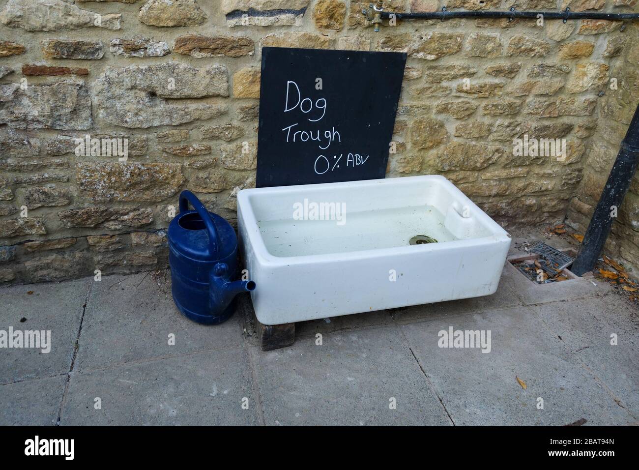 An old kitchen sink filled with water and a sign saying dog trough 0%abv outside a pub, England, UK Stock Photo
